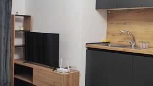 Una cocina moderna con armarios oscuros, encimera de madera y un lavamanos empotrado.