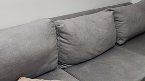 Un sofá gris con una manta beige doblada.