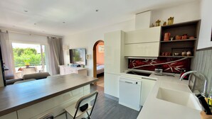 Een moderne keuken met een vaatwasser, een spoelbak en een eethoek met een tafel en stoelen.