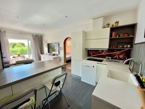 A modern kitchen with a dishwasher, a sink, and a dining area with a table and chairs. - In the heart of Saint-Aygulf, 300m from shops and beach (Fréjus)