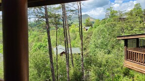 A cabin surrounded by dense forest with a mountain in the background. - Pet-Friendly | Hot Tub | Outdoor TV | Game Room | Views | Sleeps 8 (Sevierville)