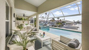 Un área junto a la piscina con asientos, vistas al puerto deportivo y cielo despejado.