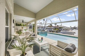 Ein Poolbereich mit Sitzgelegenheiten und Blick auf den Hafen, unter blauem Himmel.