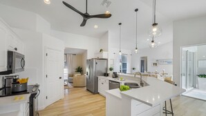 Una cocina moderna con una isla central, electrodomésticos de acero inoxidable e iluminación colgante.