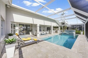 Ein moderner Poolbereich im Freien mit Liegestühlen, einer Essgegend und einer überdachten Terrasse.