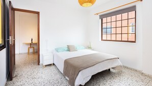 Ein Schlafzimmer mit Bett, Nachttisch, Lampe, Fenster und einer Pendelleuchte.