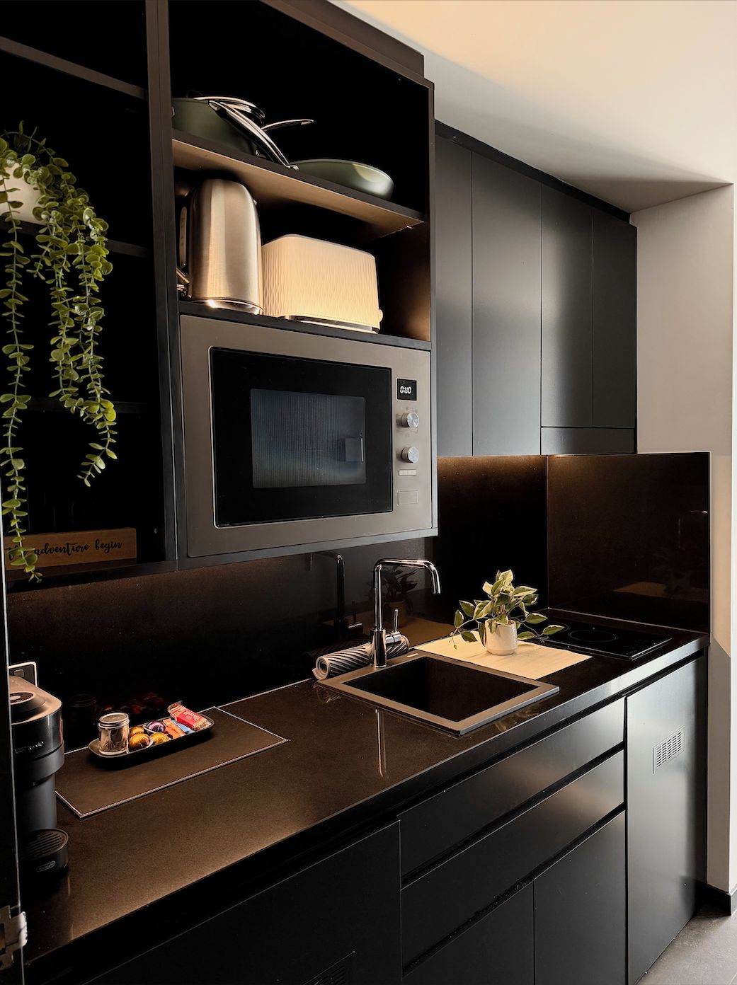 A modern kitchen with a built-in microwave, stainless steel appliances, and a black countertop.