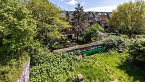 A residential building with multiple balconies, surrounded by lush greenery and a train track. - St. Pauli Urban Hideaway – Modern Apartment with Playground, Near Beach and Transport (Hamburg)