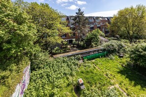 Un edificio residenziale con diversi balconi, immerso nel verde e con una linea ferroviaria nelle vicinanze.