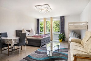 Una camera moderna con letto, divano, tavolo da pranzo, sedie e un balcone con tende.