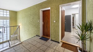 A hallway with a wooden door, a potted plant, and a metal railing. - St. Pauli Urban Hideaway – Modern Apartment with Playground, Near Beach and Transport (Hamburg)