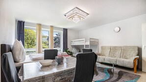 A modern living room with a dining table, sofa, and a chandelier. - St. Pauli Urban Hideaway – Modern Apartment with Playground, Near Beach and Transport (Hamburg)