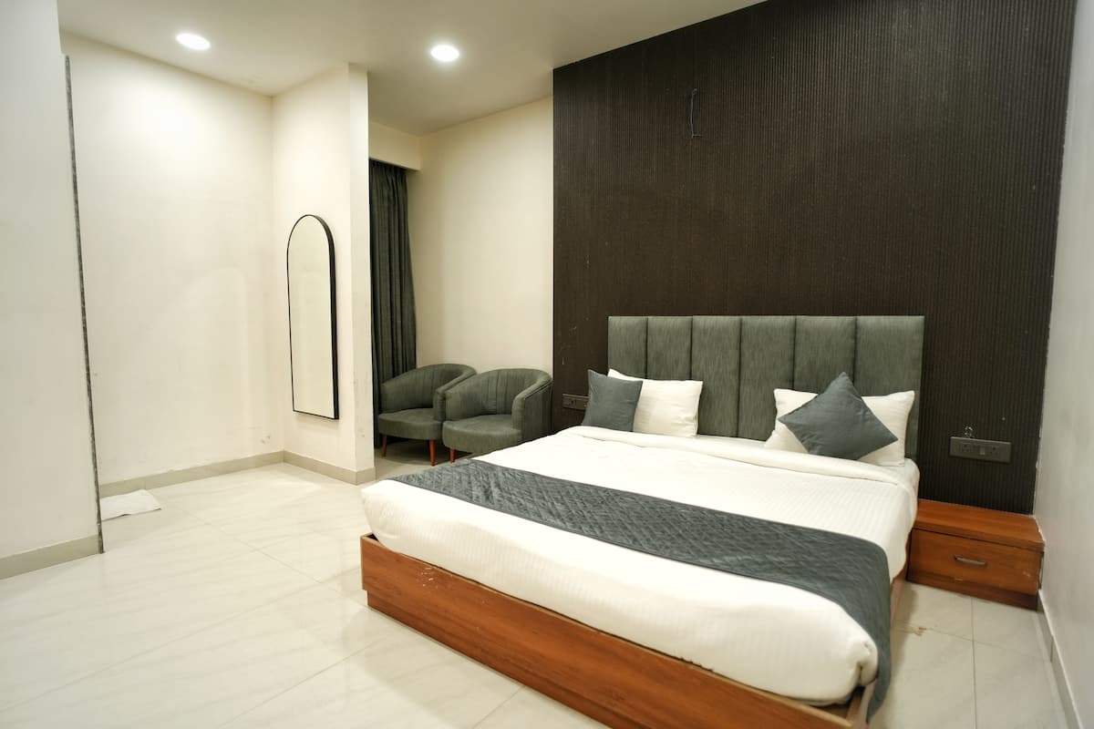 A modern bedroom with a large bed, a chair, a mirror, and a nightstand.