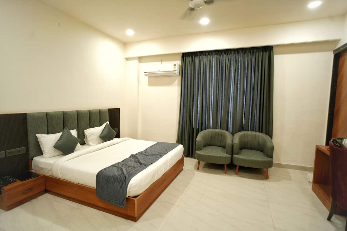 Un dormitorio con una cama, dos sillones, una mesita de noche de madera, un escritorio y un ventilador de techo.