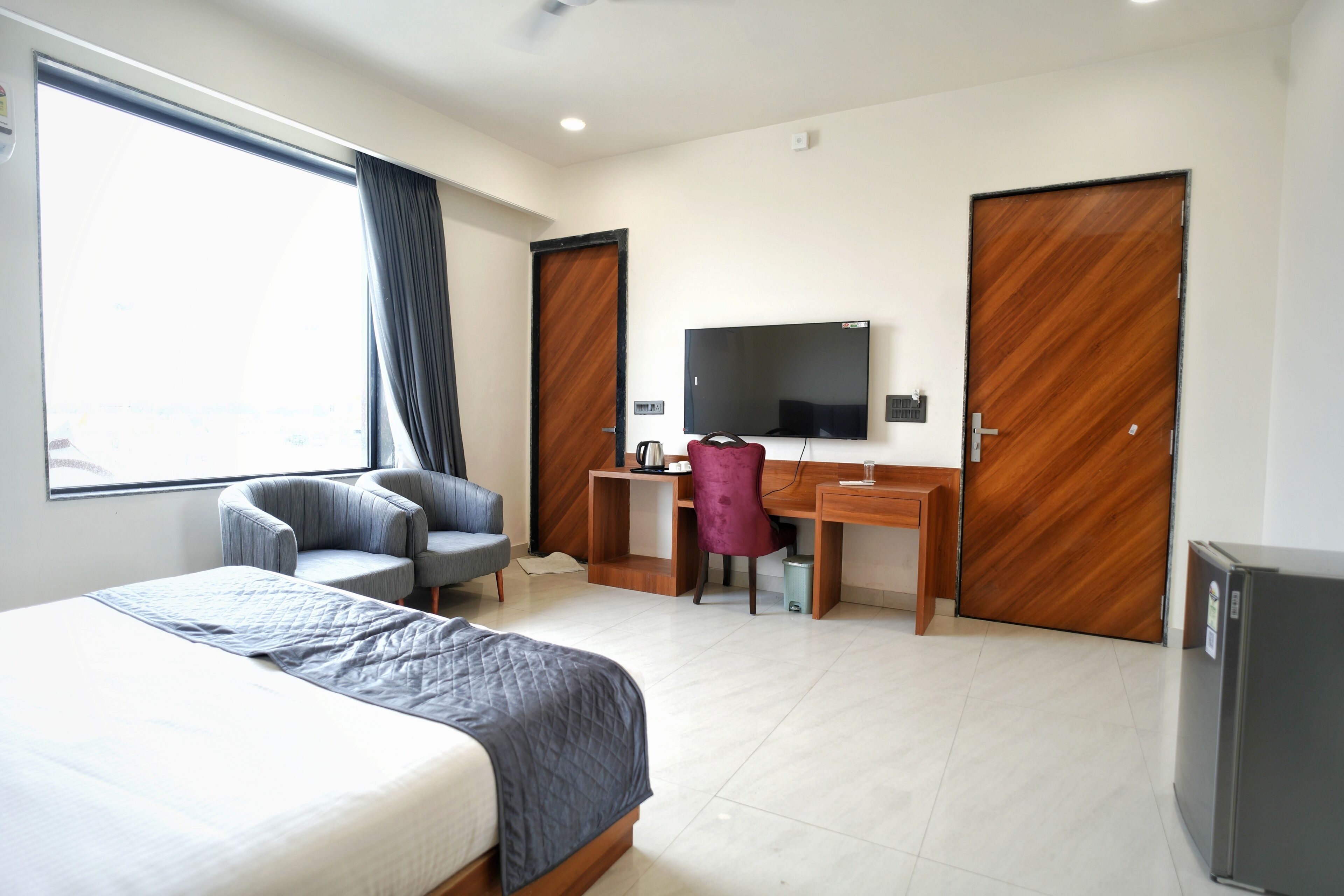 A hotel room with a bed, a desk, a chair, a television, and a wardrobe.