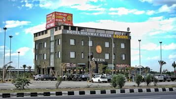Un hotel con un letrero que dice 'HOTEL HIGHWAY QUEEN & ROOMS' y un gran cartel publicitario encima.