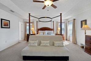 A four-poster bed with a ceiling fan, bedside lamps, and a framed picture on the wall. - 6BR Oasis w/ Private Pool, Game Room & Lanai (Davenport)