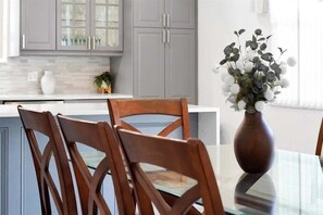 A dining area with a glass table, wooden chairs, and a vase with flowers. - 6BR Oasis w/ Private Pool, Game Room & Lanai (Davenport)