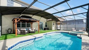 En swimmingpool med ett täckt uteområde, en pergola och utemöbler.