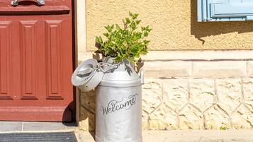 Un récipient en métal portant l’inscription « Bienvenue », placé sur une surface en pierre à côté d’une porte rouge.