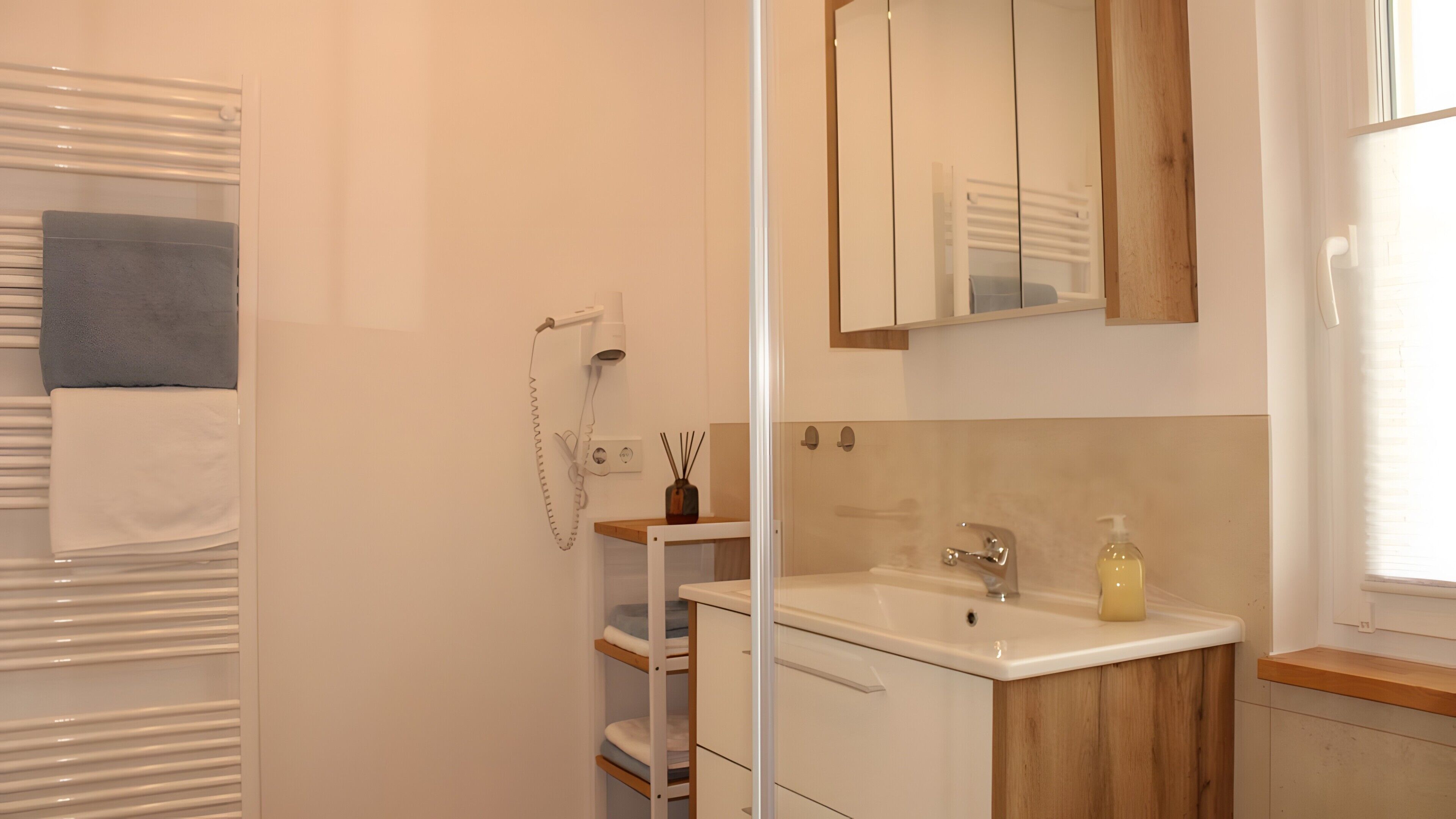 A bathroom with a shower, a sink, a mirror, and a towel rack.