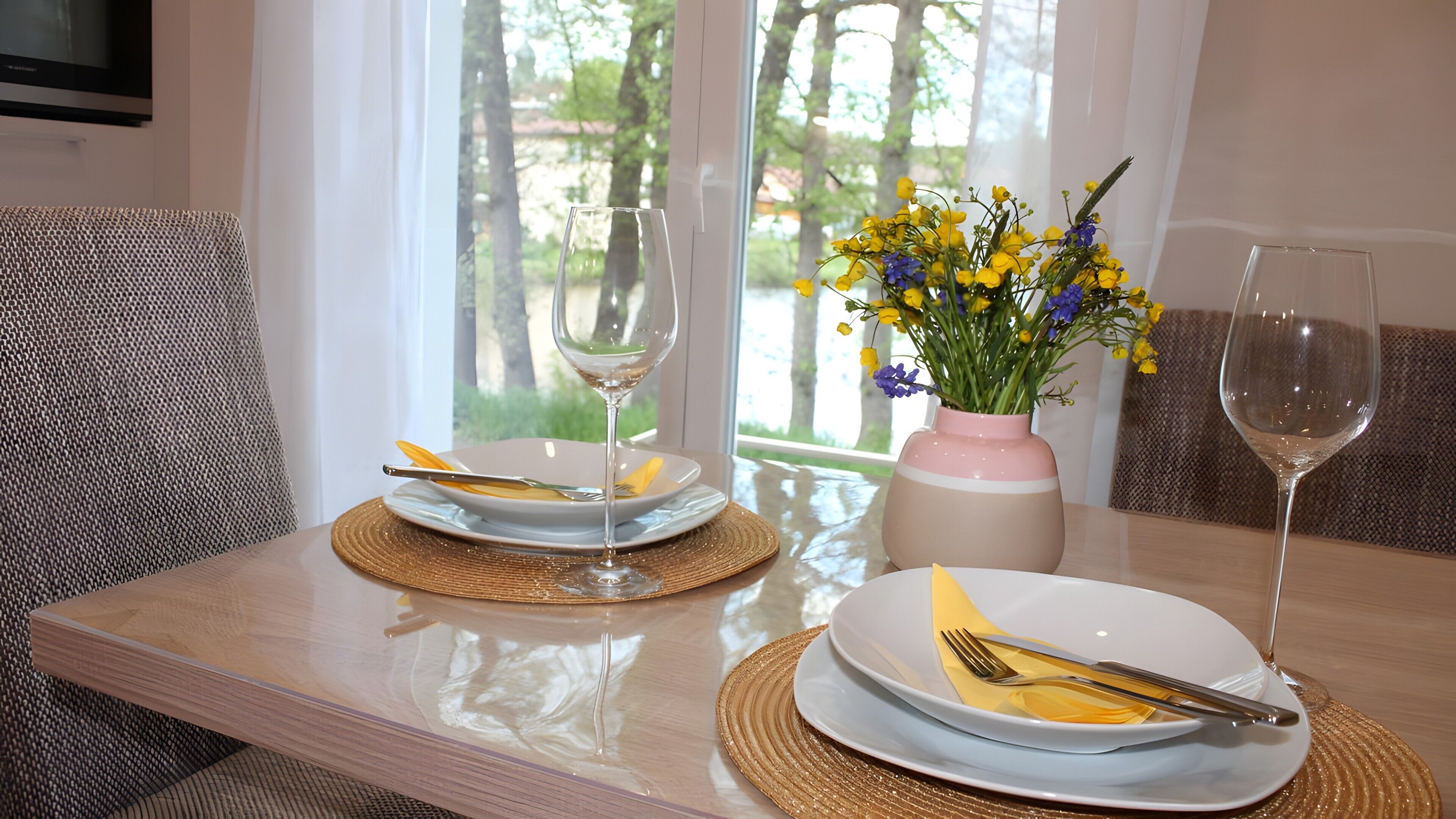 Ein Esstisch mit Tellern, Besteck und einer Blumenvase.