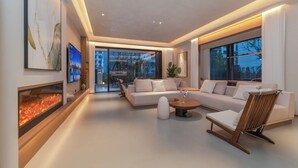 Una sala de estar moderna con chimenea, un conjunto de sofás, una mesa de centro y un ventanal grande.