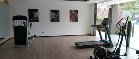 A gym with exercise equipment, including a treadmill, elliptical, and stationary bike. There are three motivational posters on the wall.