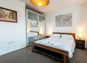 A neatly arranged hotel room with a large bed, bedside tables, a wardrobe, and a world map on the wall. - City Suites by Guestz (Chester)