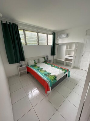 A bedroom with a bed, nightstands, a wardrobe, and a window with curtains. - Your home in Fort de France (Fort-de-France)