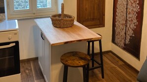 Une cuisine avec une table en bois, un panier, une cuisinière et une fenêtre donnant sur un paysage agréable.