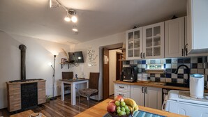 Une cuisine avec des armoires blanches, une machine à café et un panier de fruits posé sur le comptoir.