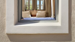 Een kamer met een bed, gordijnen en een raam met uitzicht.