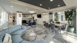 Ein moderner Wohnbereich mit Sofa, Esstisch, Stühlen und einer Küchenzeile.