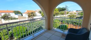 Ein Balkon mit Blick auf ein Wohngebiet, weißen Geländern und einem Stuhl.