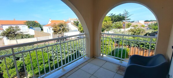 A balcony with a view of a residential area, white railings, and a chair.