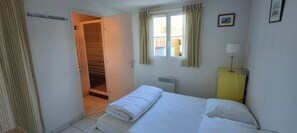 A bedroom with a bed, a window with curtains, a radiator, and a door leading to a closet. - Holiday Home for 6, 100 m from the Sea, Sea View, Shared Pool! (Bretignolles-sur-Mer)