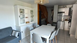 Un espacio habitable compacto con comedor, kitchenette y un sofá gris.