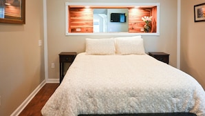 Een slaapkamer met een groot bed, een spiegel erboven en een klein nachtkastje.