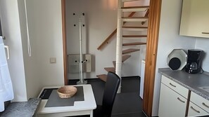 Eine kompakte Küche mit Einbauherd, einer Kaffeemaschine und einer kleinen Essecke mit Tisch und Stuhl.