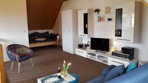 Ein modernes Wohnzimmer mit einer Couch, einem Fernseher, einem Couchtisch und einem kleinen Beistelltisch.