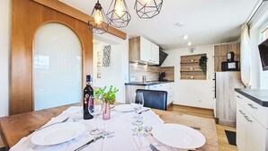 Een moderne keuken met houten kastjes, een eettafel gedekt met borden en bestek, en hanglampen.