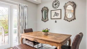 Een eetgedeelte met een houten tafel, lederen stoelen, een bank en een dakraam.