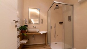 A modern bathroom with a glass-enclosed shower, a sink with a mirror, and a potted plant. - SILVANELLO Apartment (Trento)