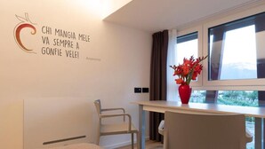 A modern room with a bed, a desk, a chair, a window with curtains, and a wall with a motivational quote. - SILVANELLO Apartment (Trento)