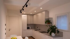 A modern kitchen with white cabinets, a microwave, a sink, and a potted plant. - SILVANELLO Apartment (Trento)