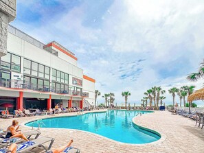 Ein Hotel mit Pool, Liegestühlen und Palmen.