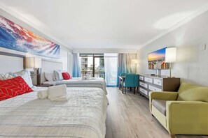 Ein Hotelzimmer mit einem Bett, zwei Nachttischen, einem Schreibtisch, einem Stuhl und einem großen Fenster.