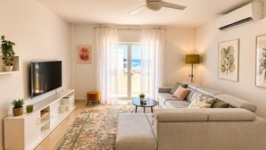 Un salon moderne avec un canapé, un téléviseur et un ventilateur de plafond.