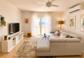Ein modernes Wohnzimmer mit einer Couch, einem Fernseher und einem Deckenventilator.